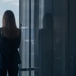 une manager face à une vitre qui renvoie son reflet, image de la connaissance de soi du manager comme miroir organisationnel